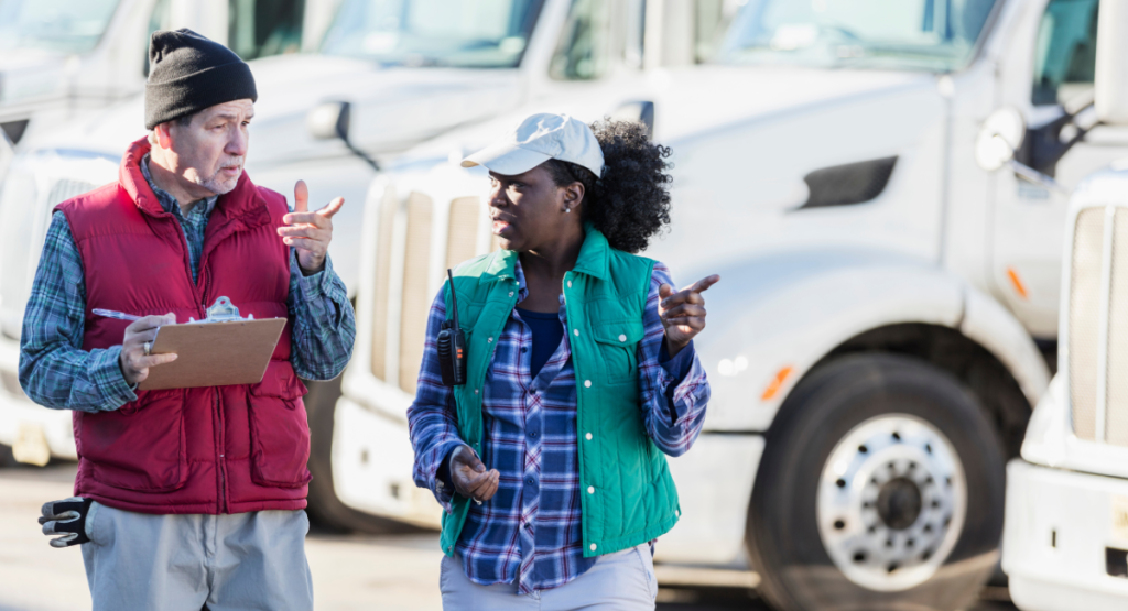 Flip A man and a woman talking in front of a fleet of trucks copy